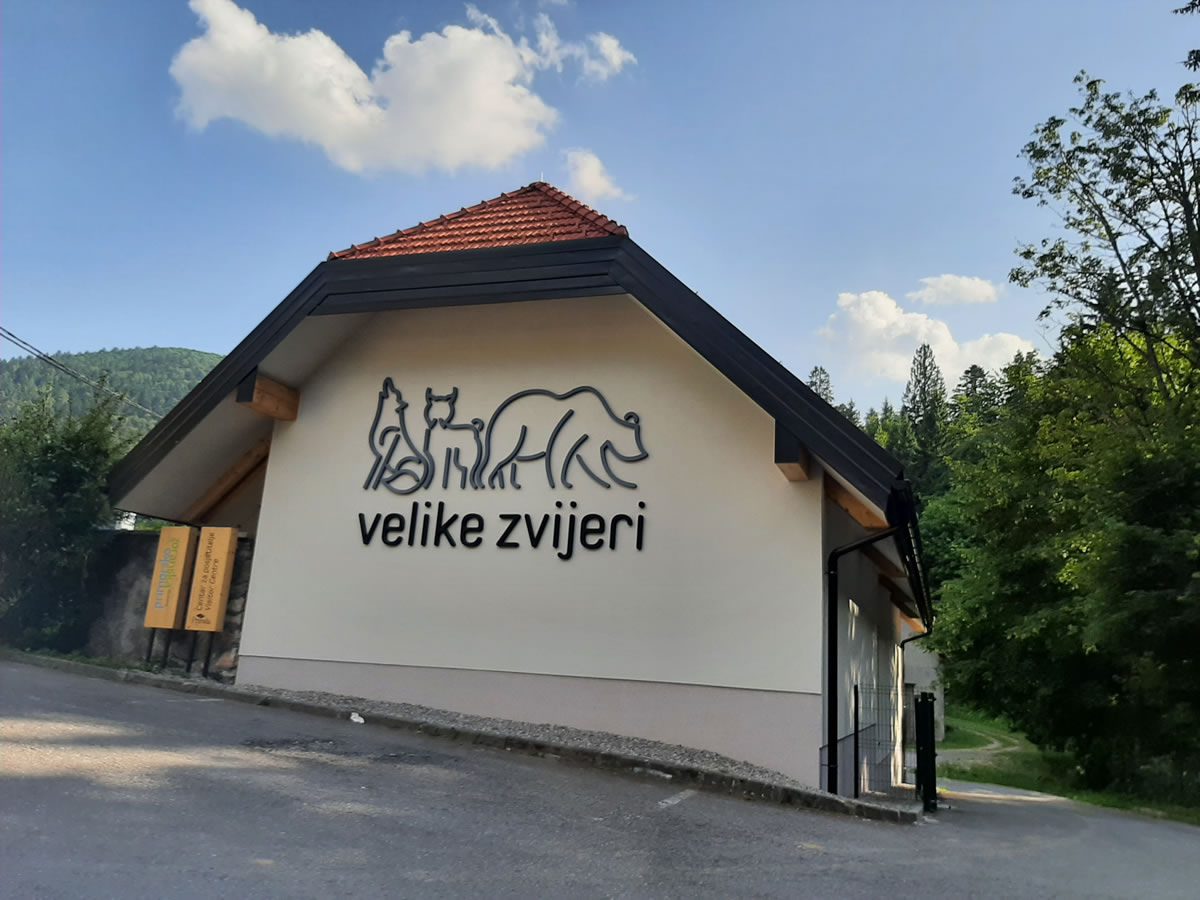Eksterijer modernog Centra za posjetitelje Velike zvijeri u Staroj Sušici s istaknutim logotipom medvjeda, vuka i risa na fasadi.